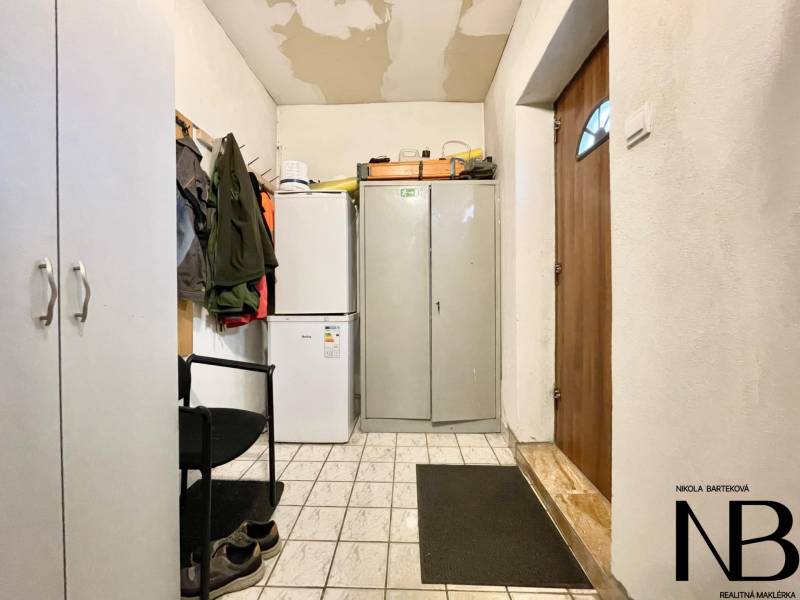 Innenraum eines Einfamilienhauses mit Kühlschrank, Schrank und Jacken an der Garderobe.