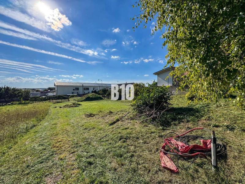 Grundstück zum Wohnen in Nitra, Grünfläche mit Vegetation und sonnigem Himmel.