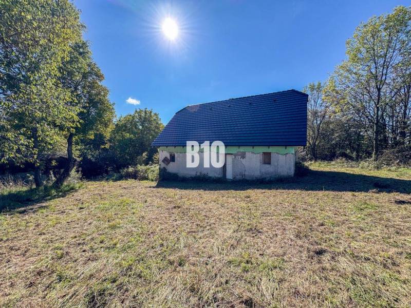 Eine Hütte in Lackov, umgeben von Natur, mit einem blauen Dach, sonniger Tag.