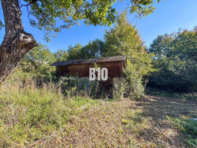 Eine Hütte in Lackov, umgeben von Gras und Bäumen an einem sonnigen Tag.