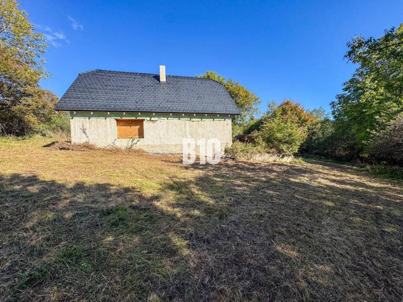 Eine Hütte in Lackov, umgeben von Natur, dargestellt in einer sonnigen Umgebung.