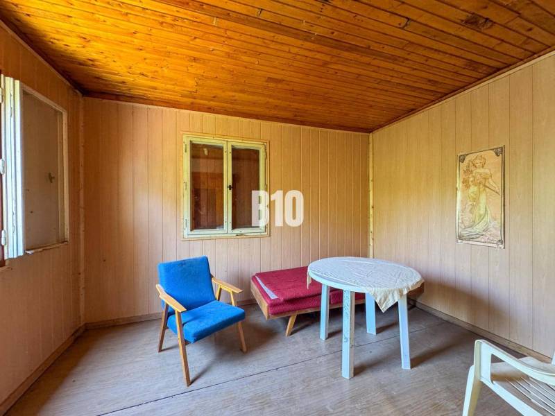 Ein hölzernes Interieur mit einem Sessel, einem Tisch und einem Bild, ideal für ein Weingut.