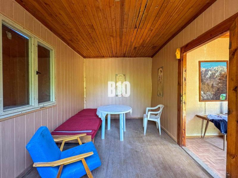 Ein Zimmer mit einer Holzdecke, einem Sessel, einem Tisch und Bildern, in den Räumlichkeiten eines Weinguts.