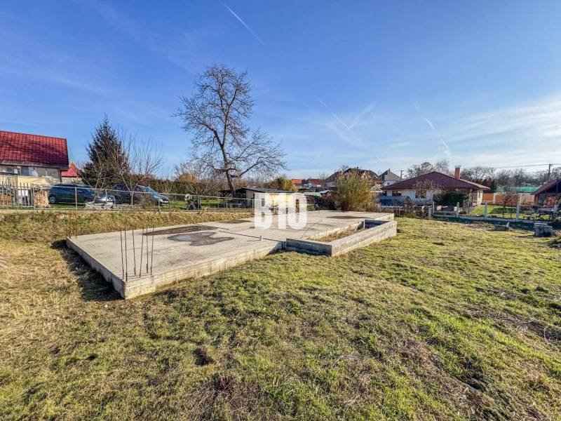 Baugrundstück mit Betonfundamenten und Grünflächen, ideal zum Wohnen.