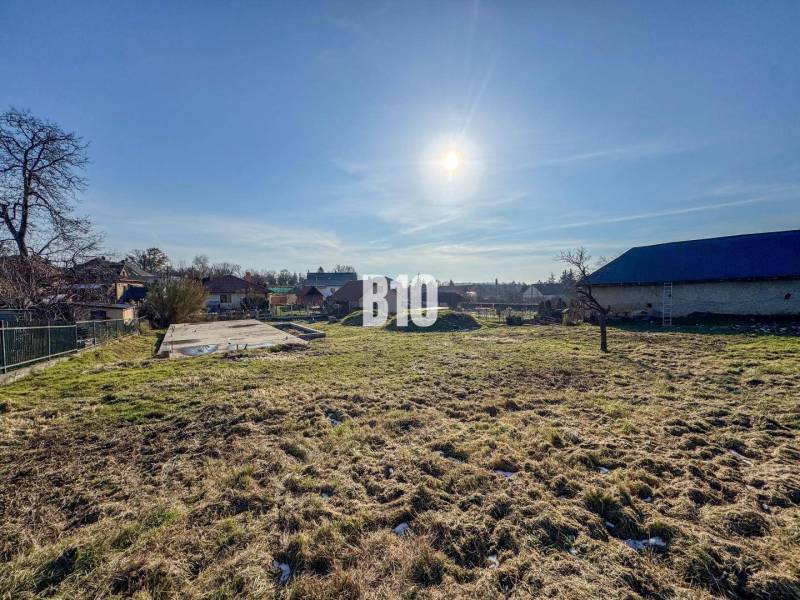 Ein Grundstück mit Betonfundament bereit zum Wohnen, sonniges Wetter und umliegende Landschaft.