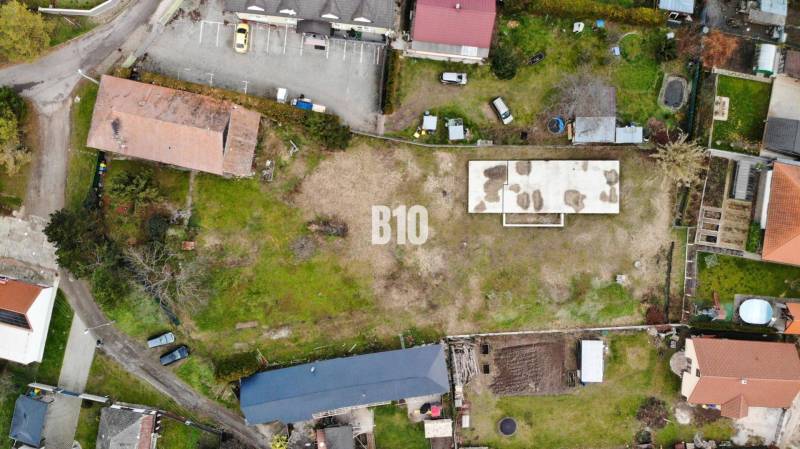 Luftaufnahme eines Grundstücks mit einem Gebäude und Parkplätzen, ideal zum Wohnen.