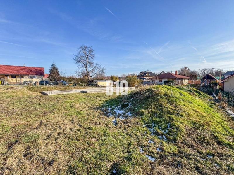 Baugrundstück, verschneites Gras, umgeben von Häusern und Dächern.