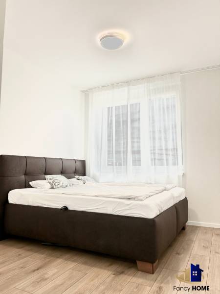 Schlafzimmer in einer 2-Zimmer-Wohnung mit Holzboden und einem bequemen Bett.