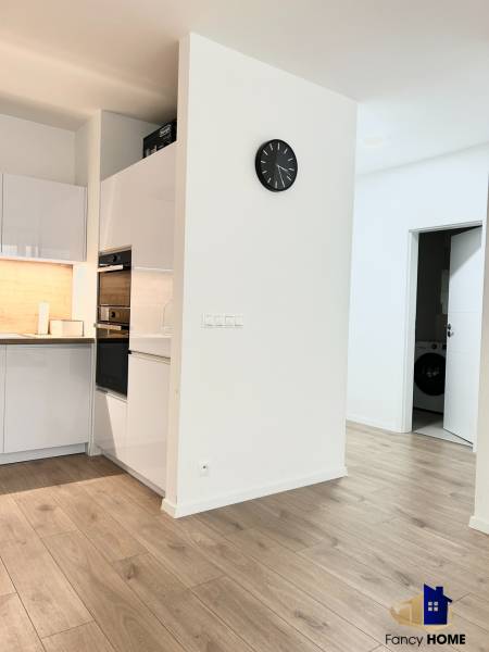 Küche in einer 2-Zimmer-Wohnung mit Holzboden und weißen Möbeln.