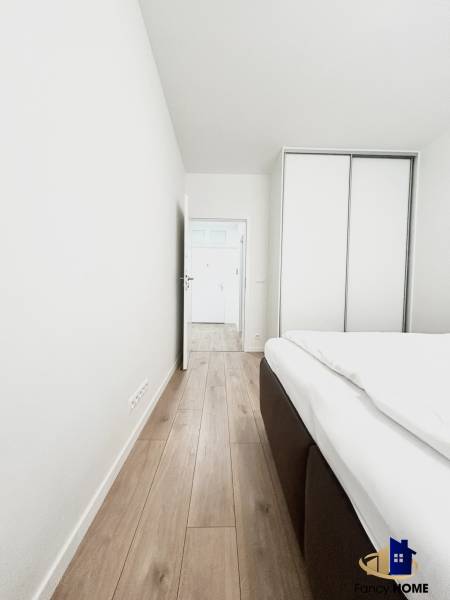 Ein Zimmer in einer 2-Zimmer-Wohnung mit einem Boden in Holzoptik und einem Einbauschrank.