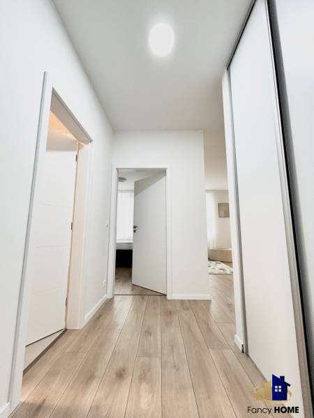 Ein Flur mit hellen Wänden und einem Boden in Holzoptik, der zu den Räumen einer Zweizimmerwohnung führt.