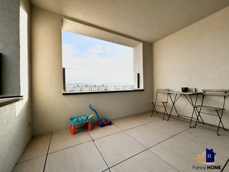 Ein Balkon mit Blick auf die Stadt, mit Spielzeug und Möbeln in einer 2-Zimmer-Wohnung.