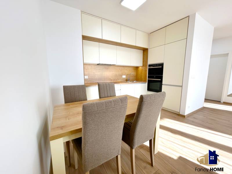 Küche in einer 2-Zimmer-Wohnung mit Esstisch und Stühlen, Boden mit Holzdekor.