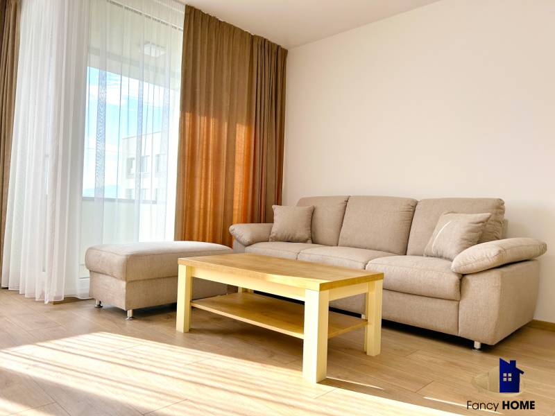 Wohnzimmer in einer 2-Zimmer-Wohnung mit Sofa, Tisch und Boden in Holzoptik.