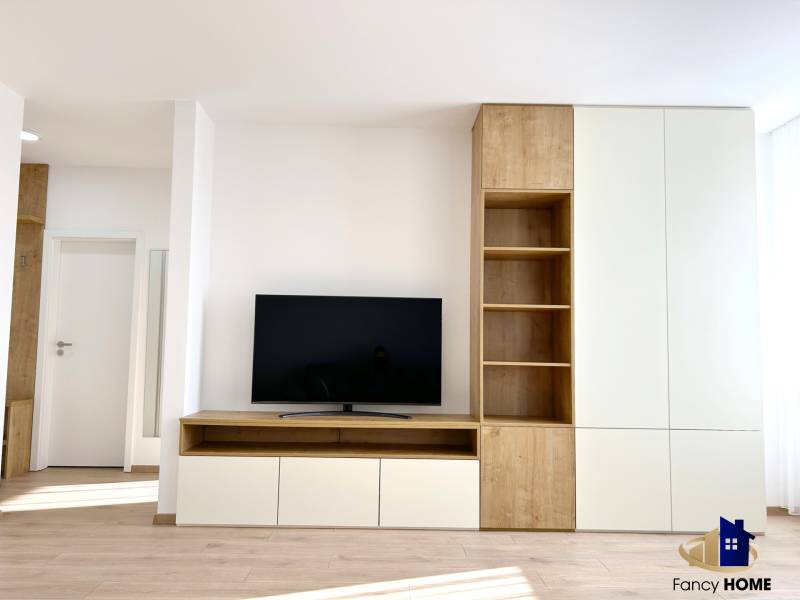 Wohnzimmer in einer 2-Zimmer-Wohnung mit Fernseher und Möbeln in Holzoptik.