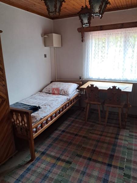 Ein Zimmer in einem Einfamilienhaus mit einem Bett, einem Fenster, einem Tisch und Stühlen.