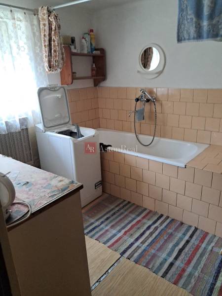 Badezimmer in einem Einfamilienhaus mit Waschmaschine, Badewanne und Spiegel an der Wand.