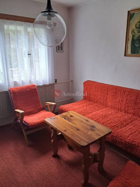 Ein Zimmer in einem Einfamilienhaus mit roten Sesseln, einem Tisch und Vorhängen mit Gardinen.