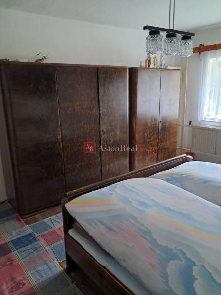 Schlafzimmer im Einfamilienhaus mit Bett, Schränken und Teppich mit buntem Muster.