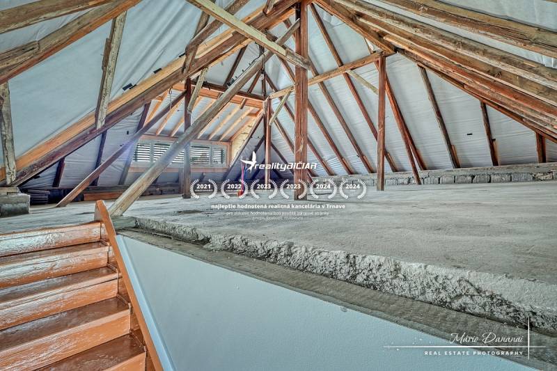 Ein Dachboden in einem Einfamilienhaus mit sichtbaren Holzbalken und einer Treppe.