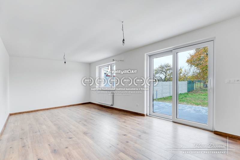 Ein Interieur in einem Einfamilienhaus mit einem Boden in Holzoptik und großen Fenstern.