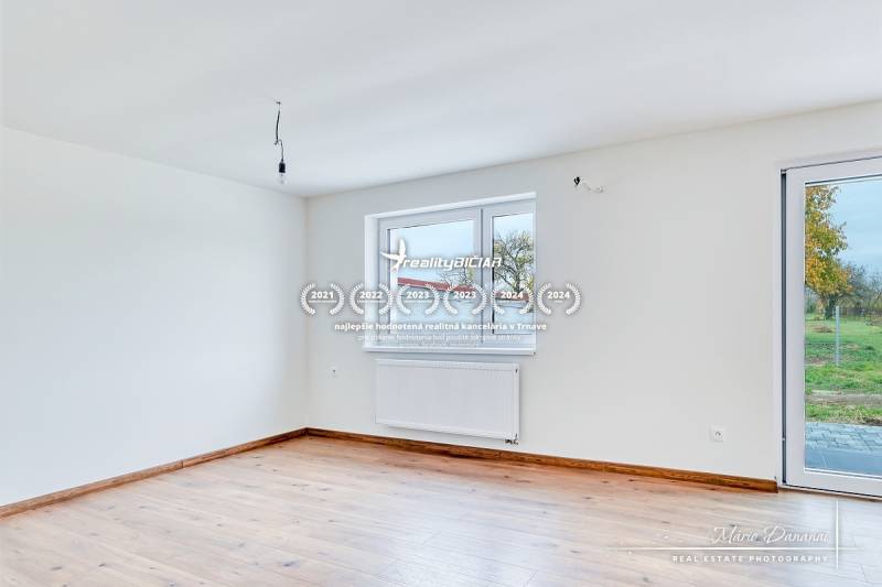 Ein geräumiges Zimmer in einem Einfamilienhaus mit einem Holzboden und großen Fenstern.