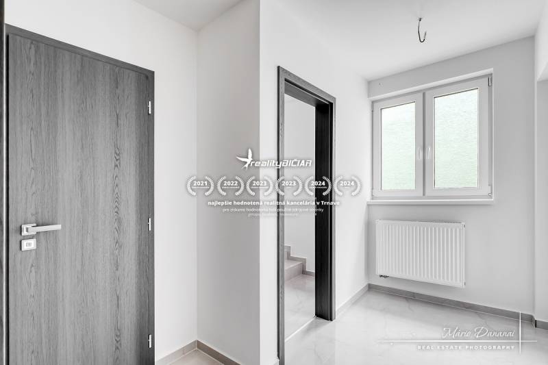 Innenraum eines Einfamilienhauses mit weißen Wänden, Kunststofffenstern und Türen mit Holzdekor.