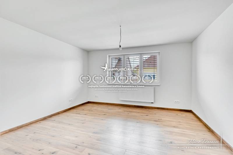 Ein leerer Raum in einem Einfamilienhaus mit Holzboden und weißen Wänden.