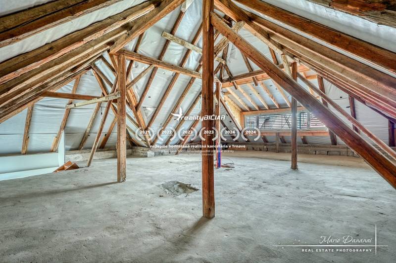 Dachboden eines Einfamilienhauses mit Holzbalken und unbehandeltem Boden.