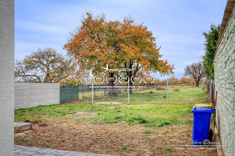 Der Garten des Einfamilienhauses in der Orechová-Straße in Jaslovské Bohunice mit einem Herbstbaum und einem Zaun.