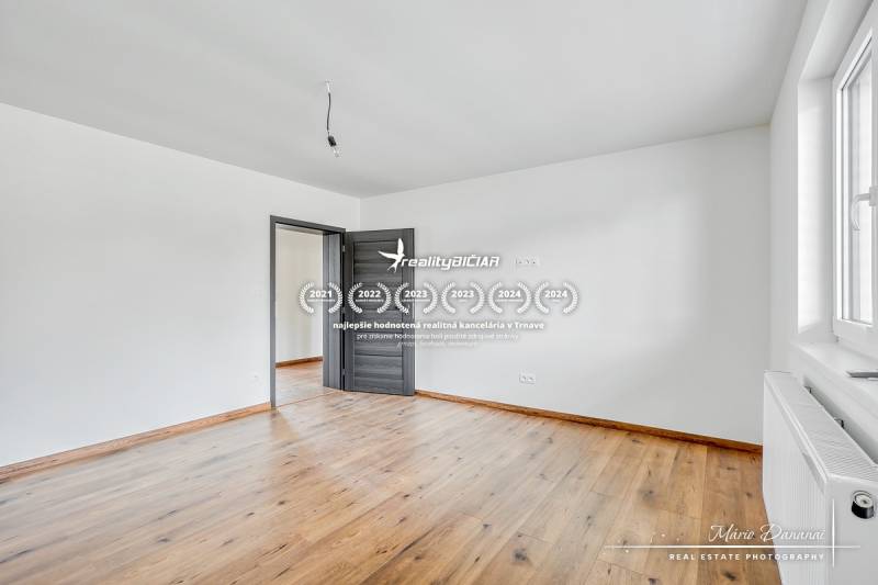 Ein Zimmer in einem Einfamilienhaus mit weißen Wänden und einem Boden in Holzoptik.