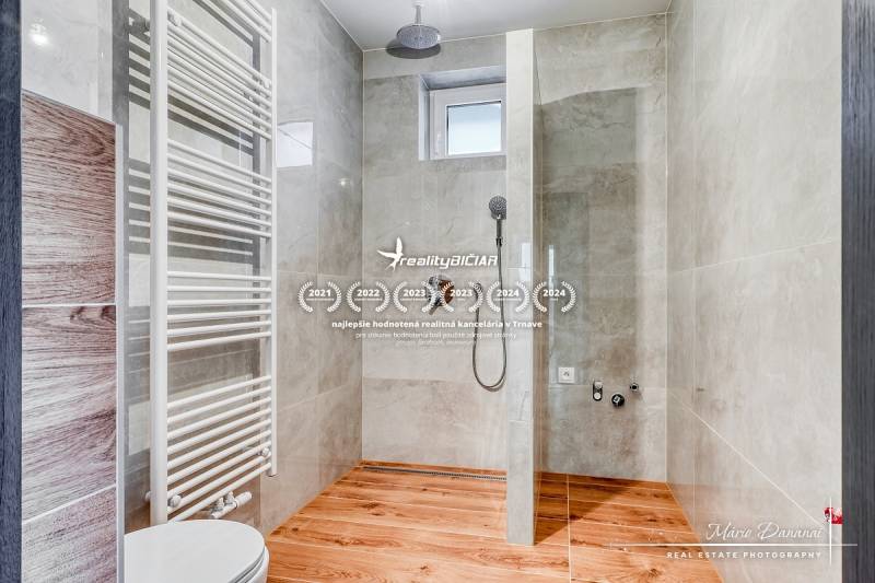 Duschkabine im Einfamilienhaus mit Boden in Holzoptik und hellen Fliesen.