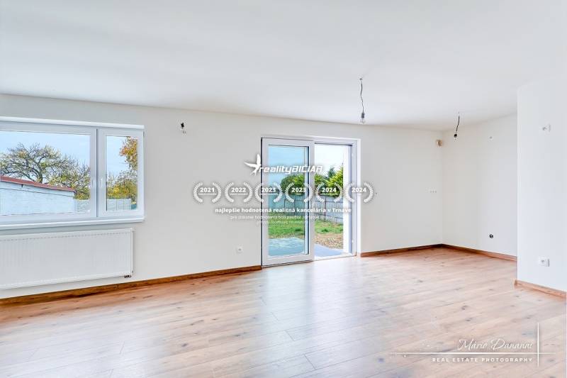 Helles Zimmer mit Holzboden in einem Einfamilienhaus, große Fenster, Zugang zur Terrasse.