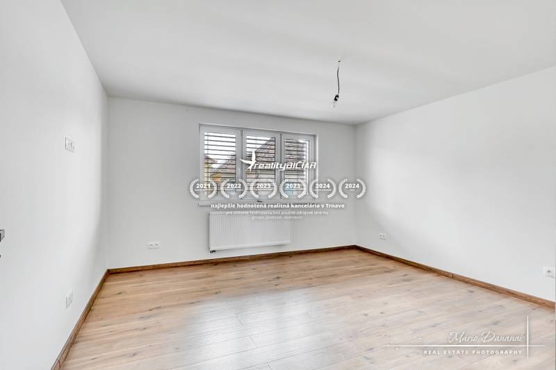 Ein Zimmer mit weißen Wänden und einem Boden in Holzoptik in einem Einfamilienhaus.