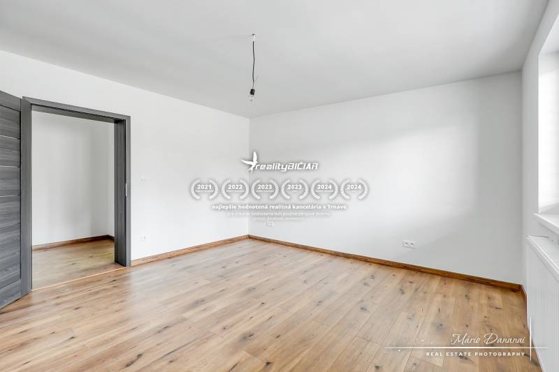 Ein Zimmer mit weißen Wänden und einem Boden in Holzoptik in einem Einfamilienhaus.