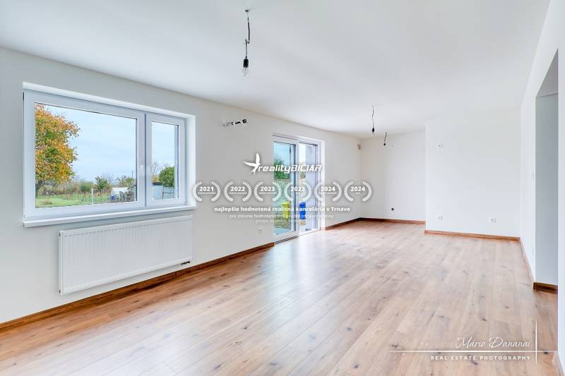 Geräumiges Wohnzimmer in einem Einfamilienhaus mit Holzboden und großen Fenstern.