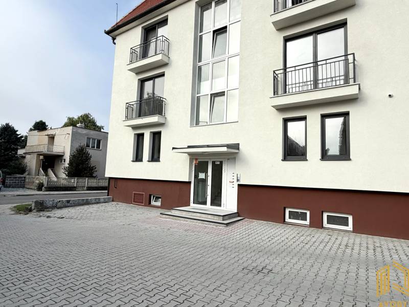 Das Gebäude in der Sadová-Straße in Senica mit weißer Fassade und gepflastertem Parkplatz.