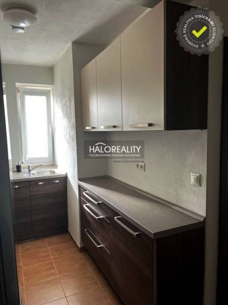 Küche in einer 3-Zimmer-Wohnung mit dunklen Schränken und einem Fenster.