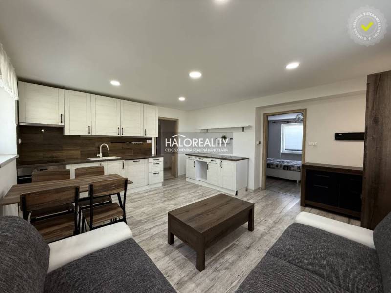 Wohnzimmer mit Küchenzeile in einer 3-Zimmer-Wohnung, enthält Holzelemente und Möbel.