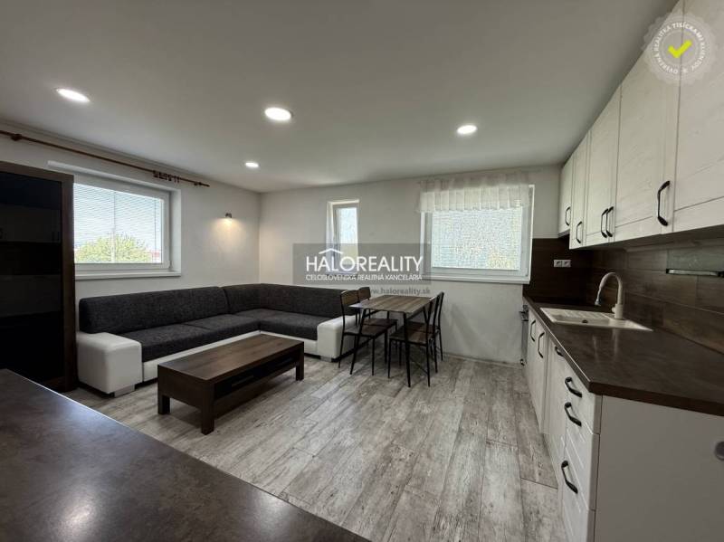 Wohnzimmer mit Küche, heller Boden, graues Sofa, Esstisch in einer 3-Zimmer-Wohnung.