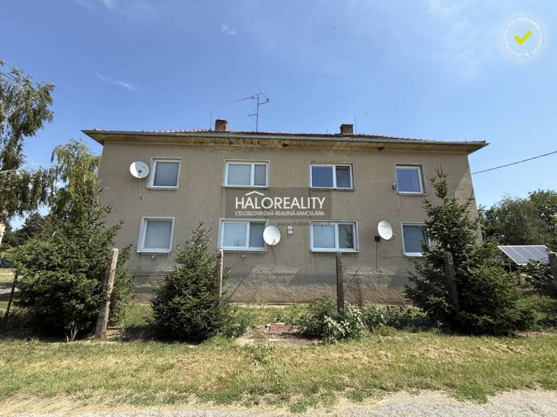 Ein Wohnhaus umgeben von Grünflächen in Bošany mit mehreren Satellitenschüsseln an der Fassade.