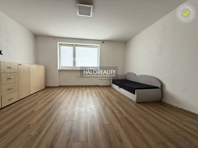 Ein Zimmer mit Holzboden, einem Sofa und einer Kommode in einer 3-Zimmer-Wohnung.