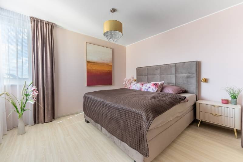 Schlafzimmer in einem Einfamilienhaus mit Bett, Bild, Lampe und Boden mit Holzdekor.