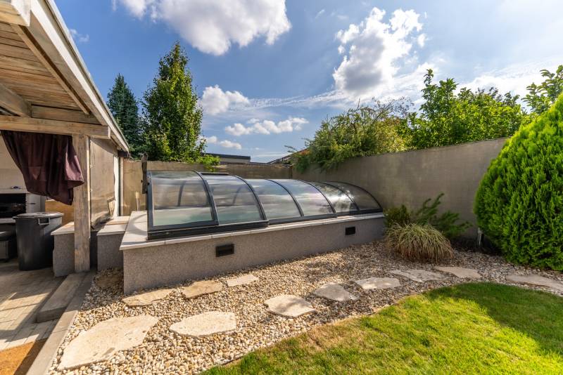 Der Garten des Einfamilienhauses in der Jazdecká-Straße in Trnava mit überdachtem Pool und Grünflächen.