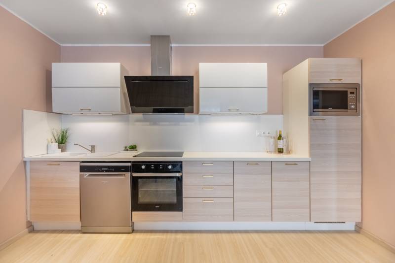 Eine Küche in einem Einfamilienhaus mit Küchenzeile, Einbaugeräten und einem Boden in Holzoptik.