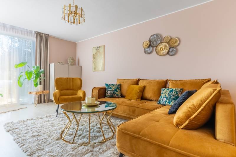 Wohnzimmer in einem Einfamilienhaus mit einem senffarbenen Sofa und einem Tisch auf einem Boden mit Holzdekor.