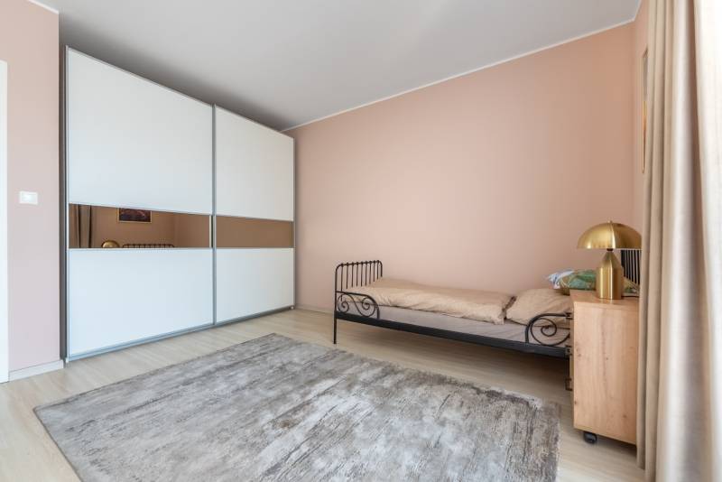 Ein Zimmer in einem Einfamilienhaus mit einem Metallbett, einem Schrank und einem Boden mit Holzdekor.