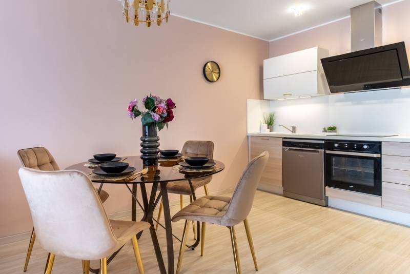 Esszimmer mit rundem Tisch und Küchenzeile in einem Einfamilienhaus, Boden mit Holzdekor.