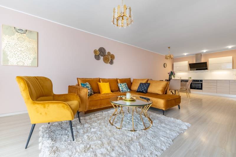 Wohnzimmer in einer 4-Zimmer-Wohnung mit einem bequemen Sofa und einem Boden in Holzoptik.