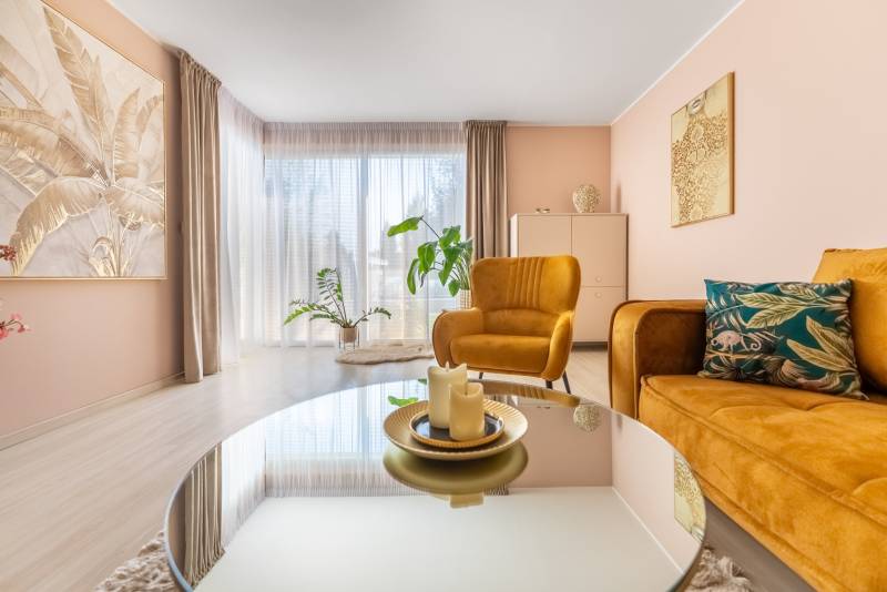 Wohnzimmer eines Einfamilienhauses mit bequemen Sesseln, dekorativen Pflanzen und einem Boden in Holzoptik.